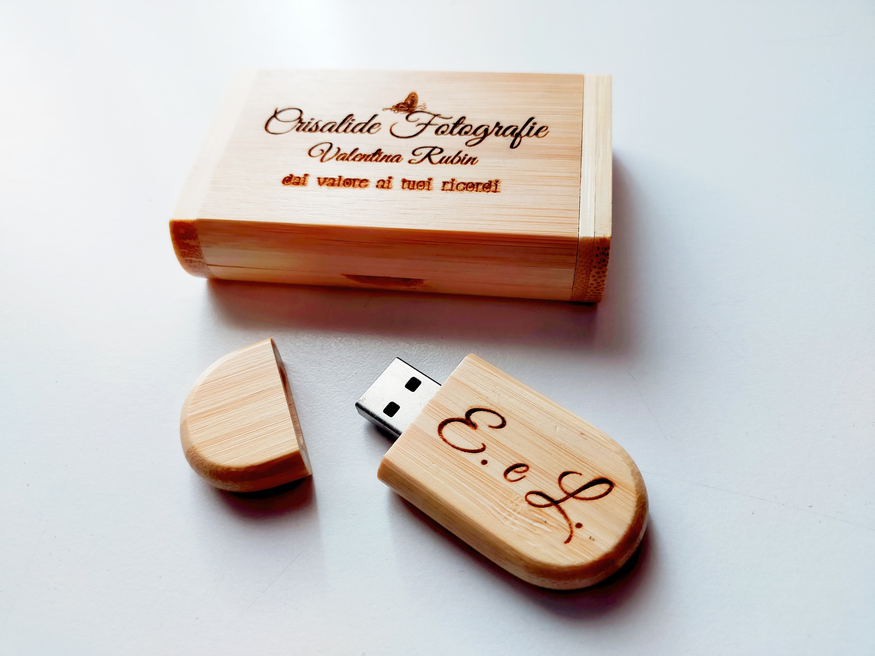 Chiavetta USB in legno con iniziali incise a laser e scatolina coordinata con logo inciso, appoggiate su un tavolo bianco