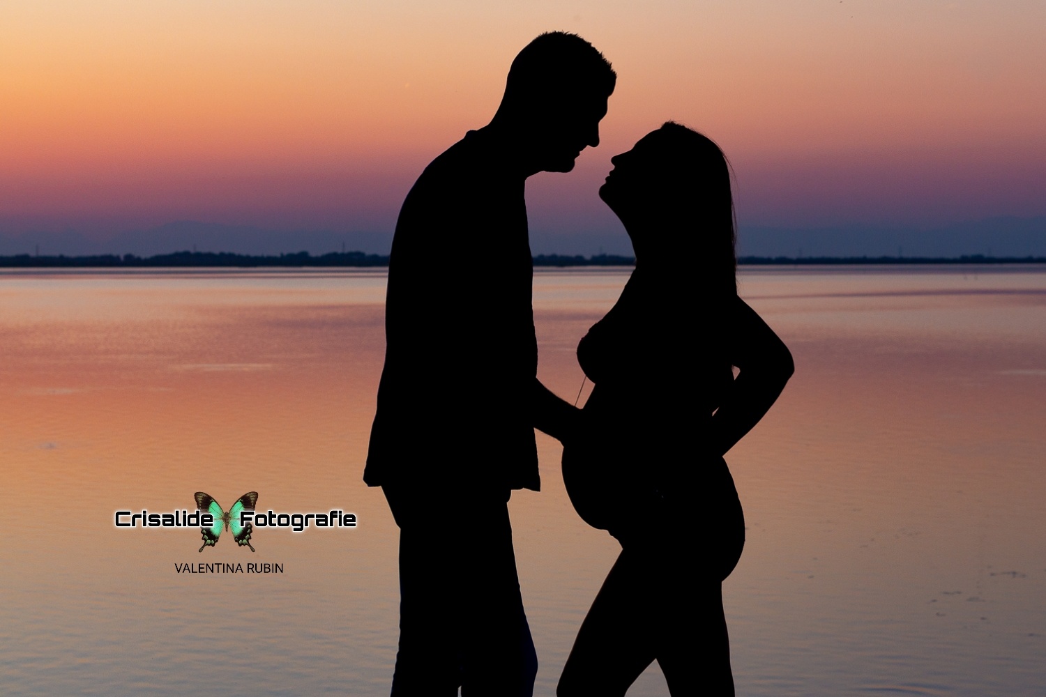 Silhouette di coppia al tramonto che si sfiorano le labbra, sfondo mare e tramonto violaceo