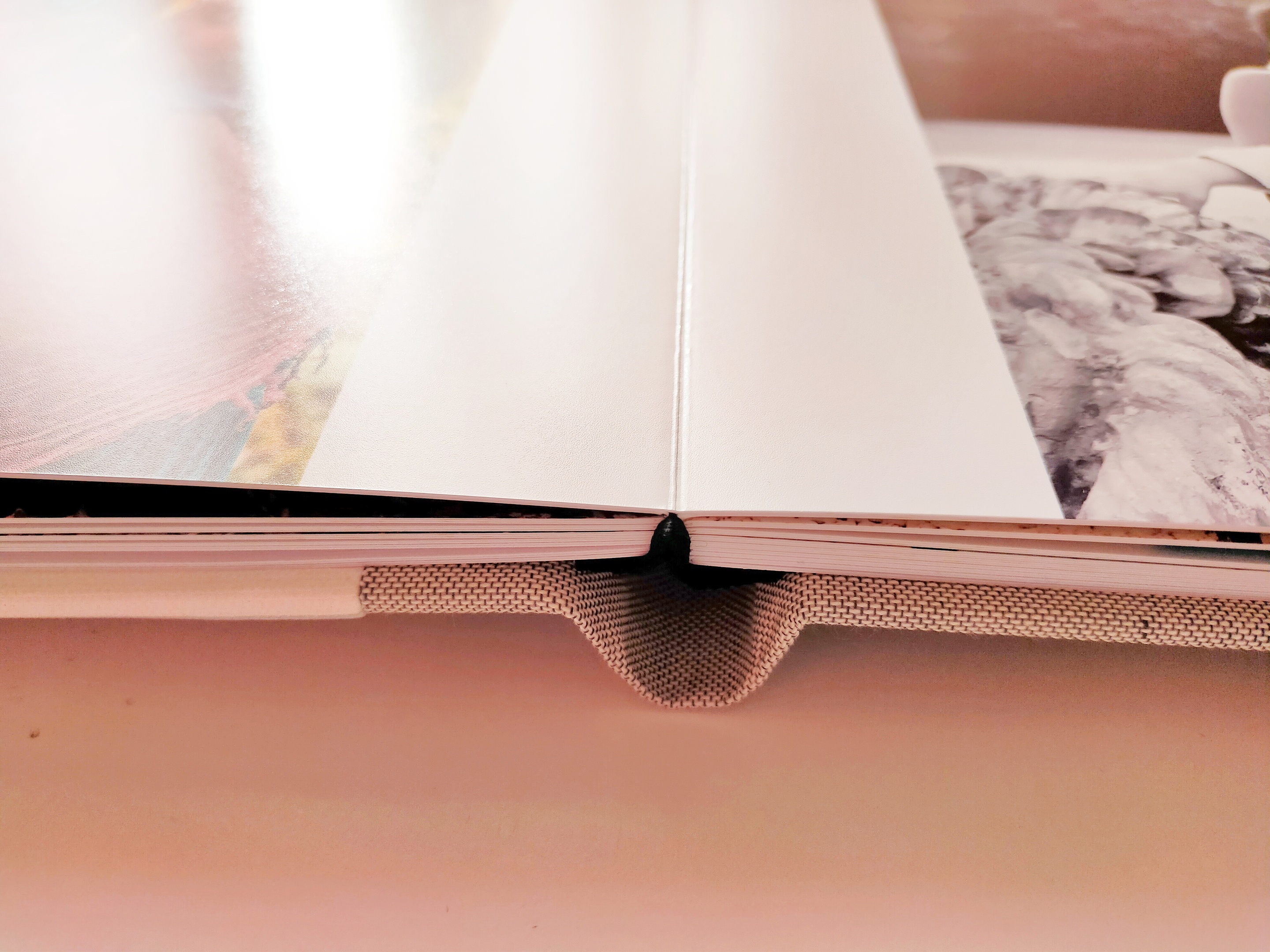 Dettaglio di album fotografico aperto, centrato tra le due pagine per mostrare l'apertura a 180°. Evidenziata la qualità delle pagine rigide e spesse e la stampa diretta delle foto. Sfondo bianco