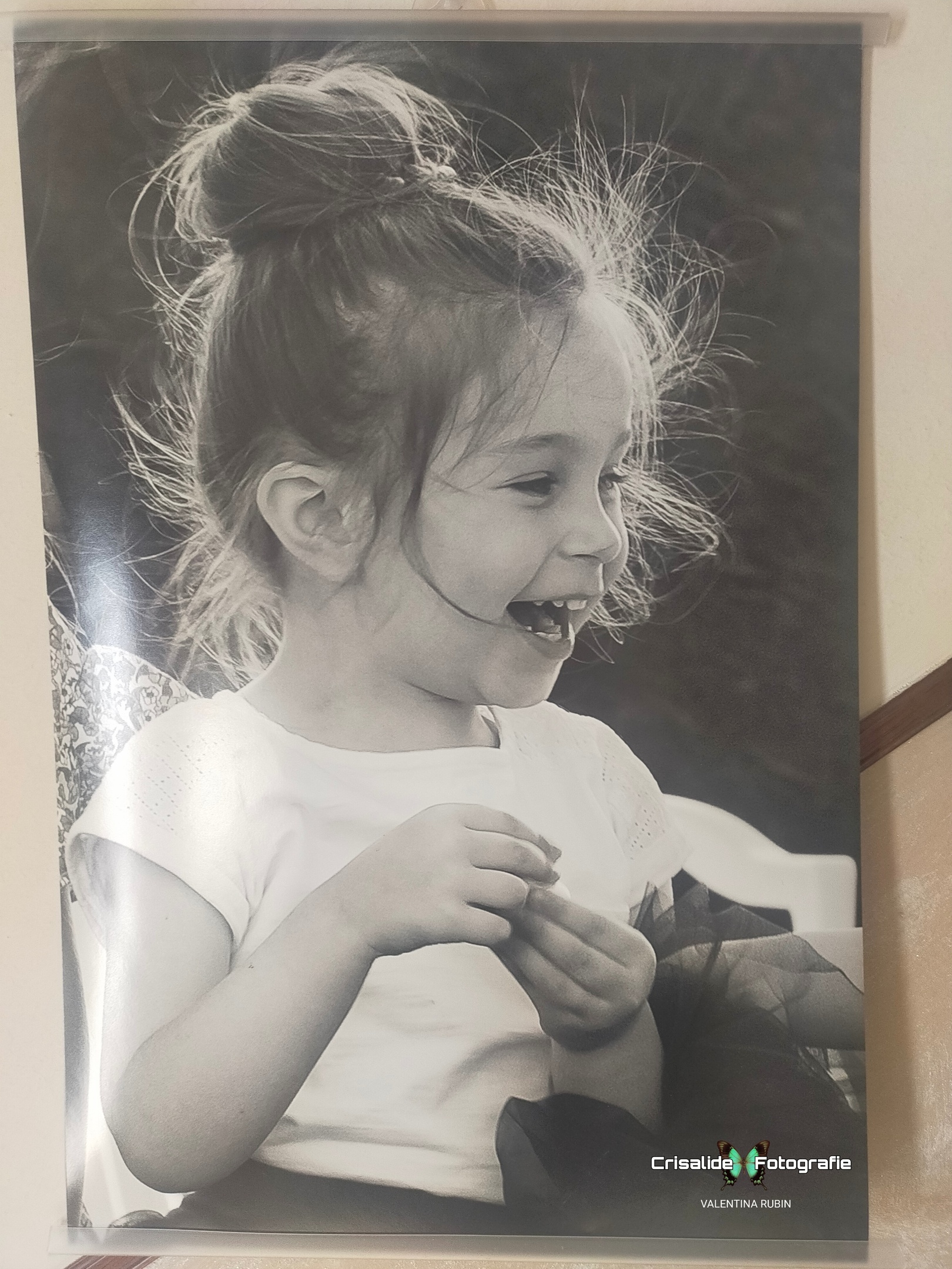 Bambina con maglia bianca a maniche corte e gonna in tulle nera, capelli raccolti in un chignon, sorridente mentre guarda di lato, tiene qualcosa in mano