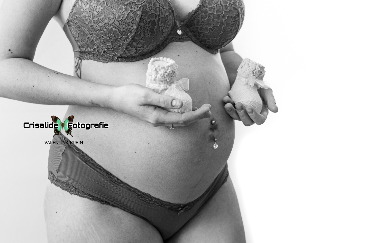 Servizio fotografico di maternità a domicilio a Padova: primo piano in bianco e nero di una futura mamma che tiene in mano delle piccole scarpette