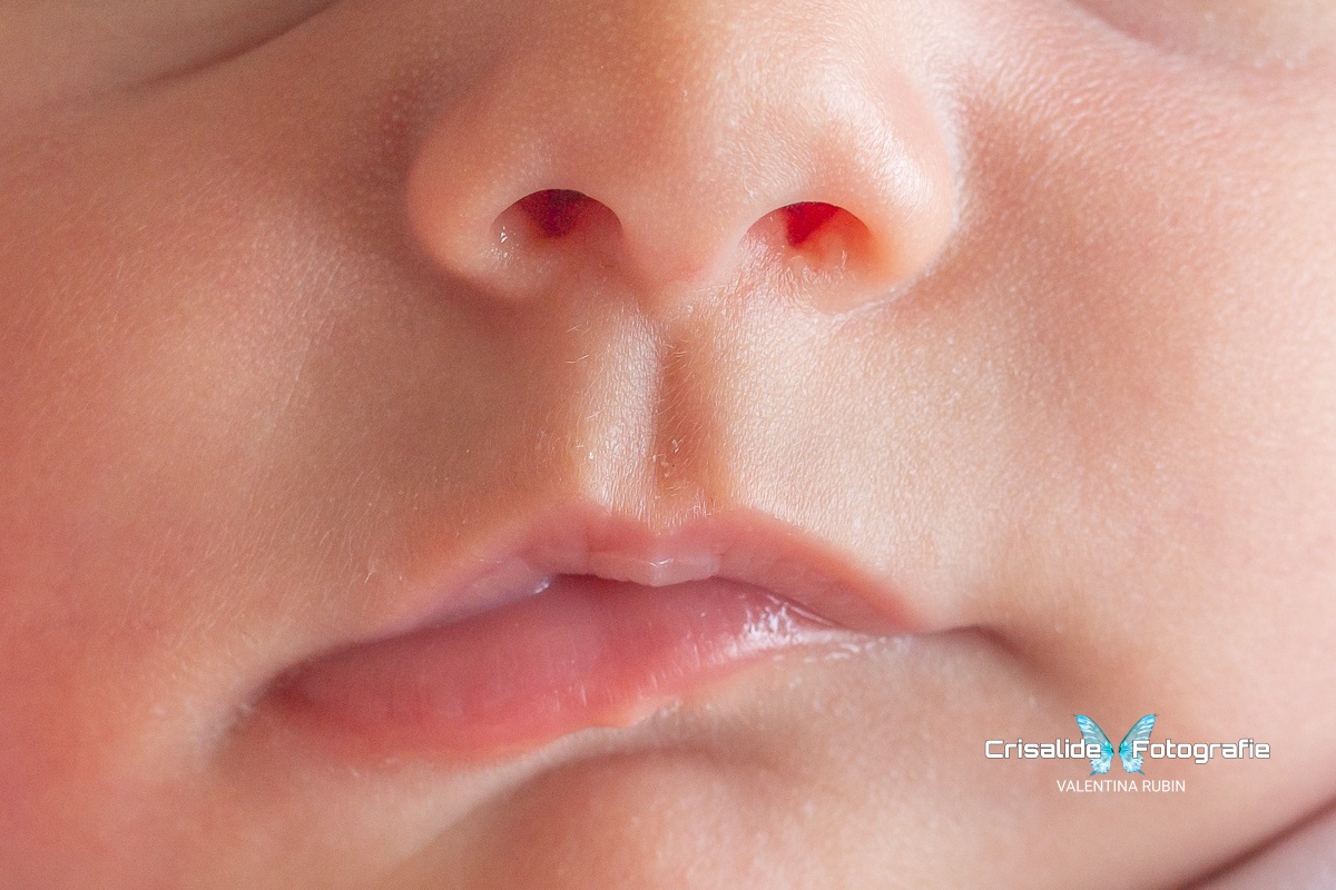 Dettaglio della bocca e del nasino di una neonata che dorme profondamente con le labbra leggermente storte