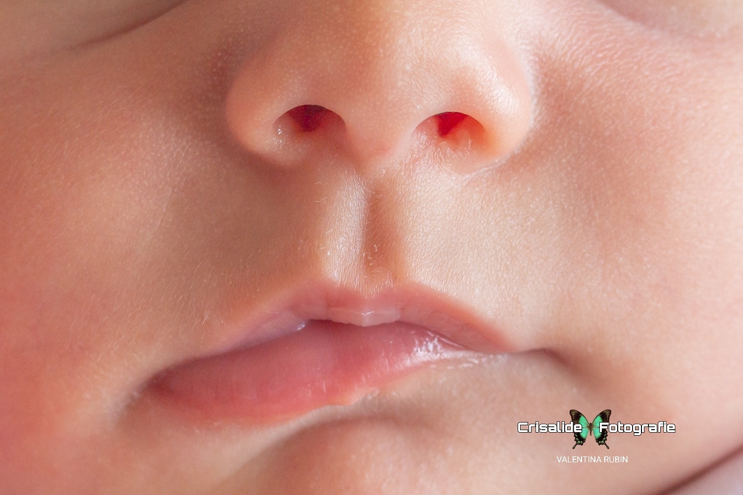 Dettaglio della bocca e del nasino di una neonata che dorme profondamente con le labbra leggermente storte