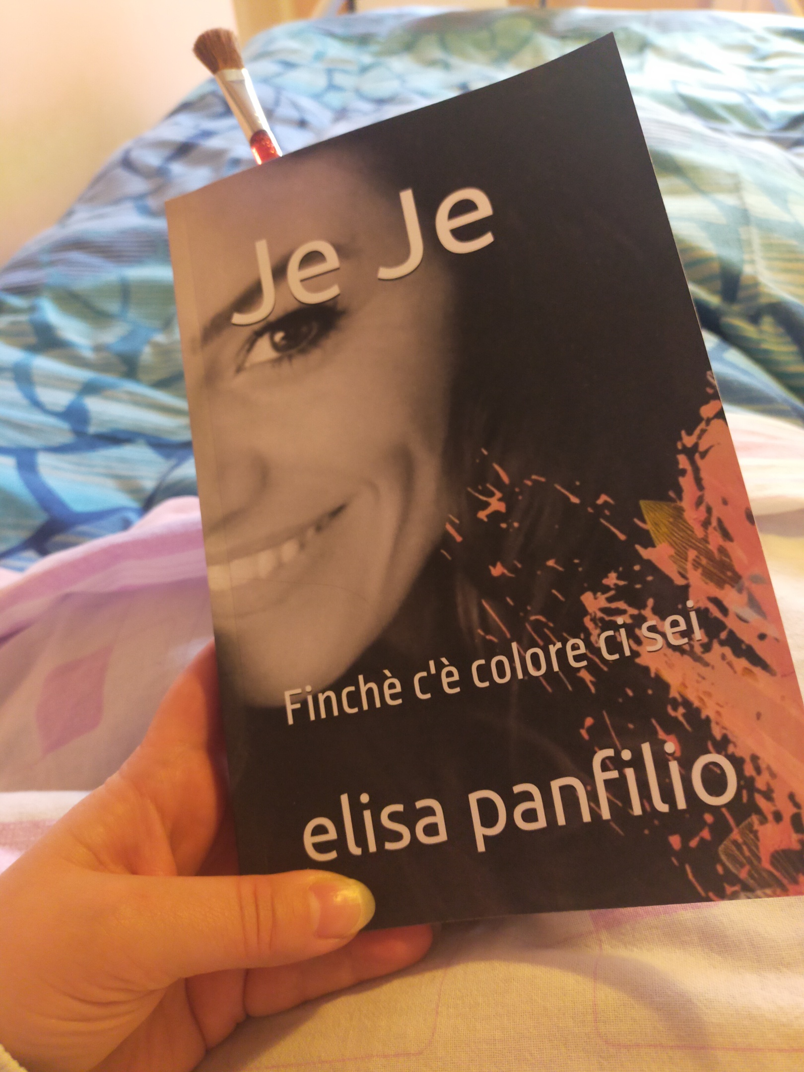 La fotografa Valentina tiene in mano il libro biografico dedicato a Jenny Corrò, intitolato 'Je Je - Finchè c'è colore ci sei' di Elisa Panfilio, usando un pennellino da trucco come segnalibro