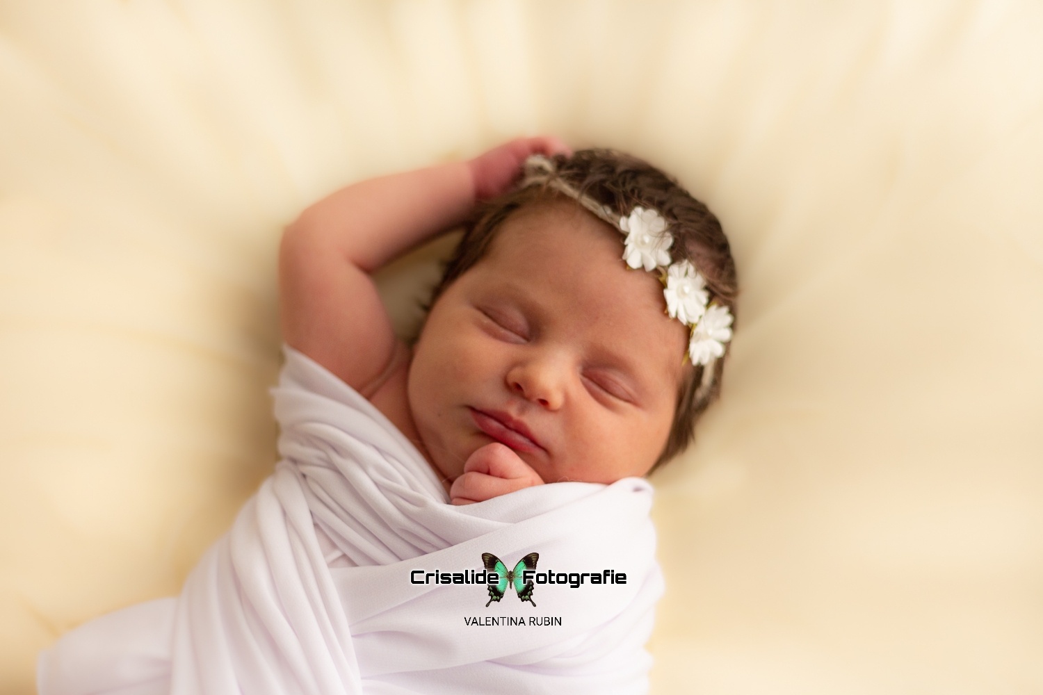 Neonata di 14 giorni che dorme, fasciata di bianco con coroncina di fiori, manina sopra la testa, sfondo biege