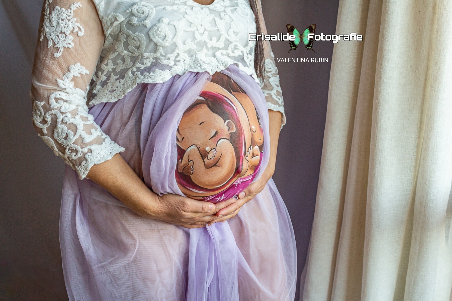 Primo piano del pancione di una mamma incinta, dipinto con belly painting. Sfondo tenda