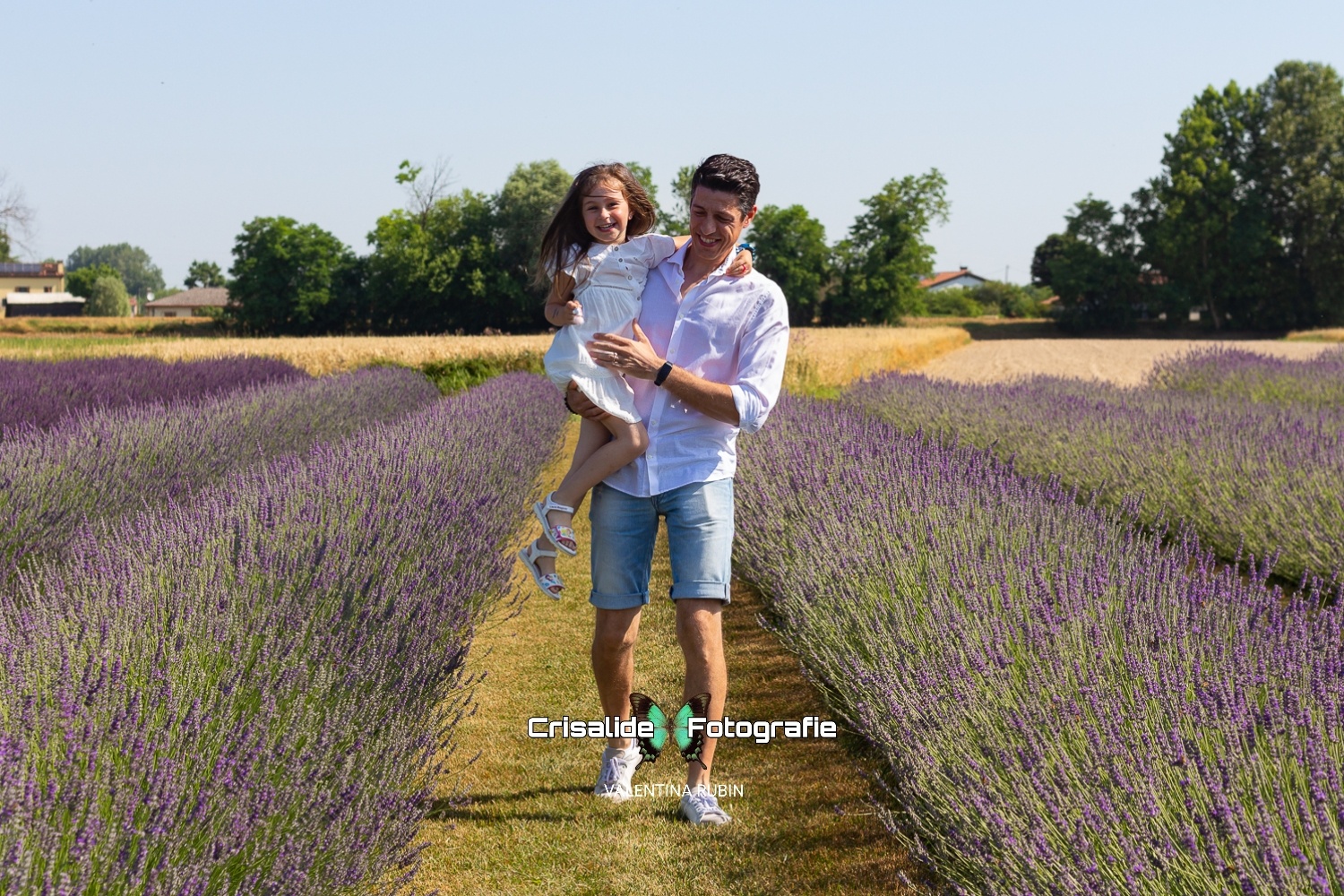 Papà e figlia abbracciati sorridenti tra i filari di lavanda