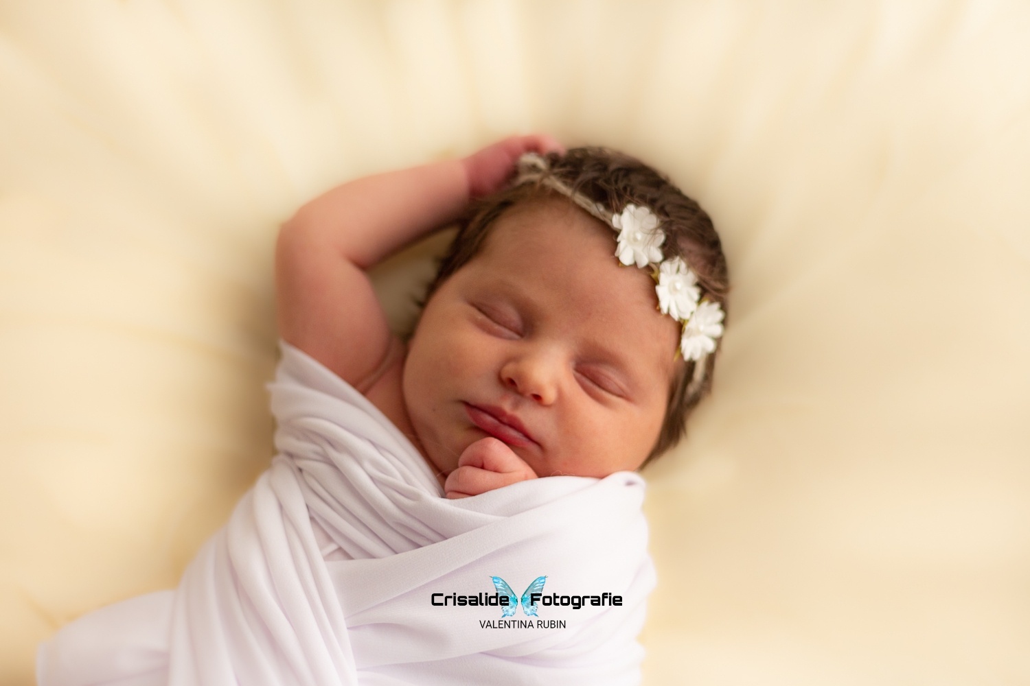 Neonata di 14 giorni che dorme, fasciata di bianco con coroncina di fiori, manina sopra la testa, sfondo biege