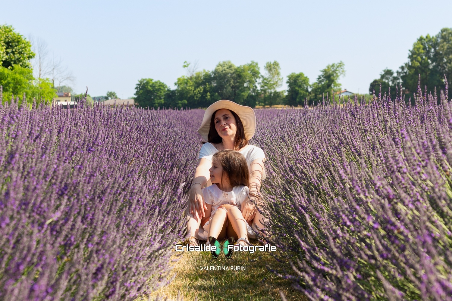 Mamma e bambina sedute tra i filari di lavanda