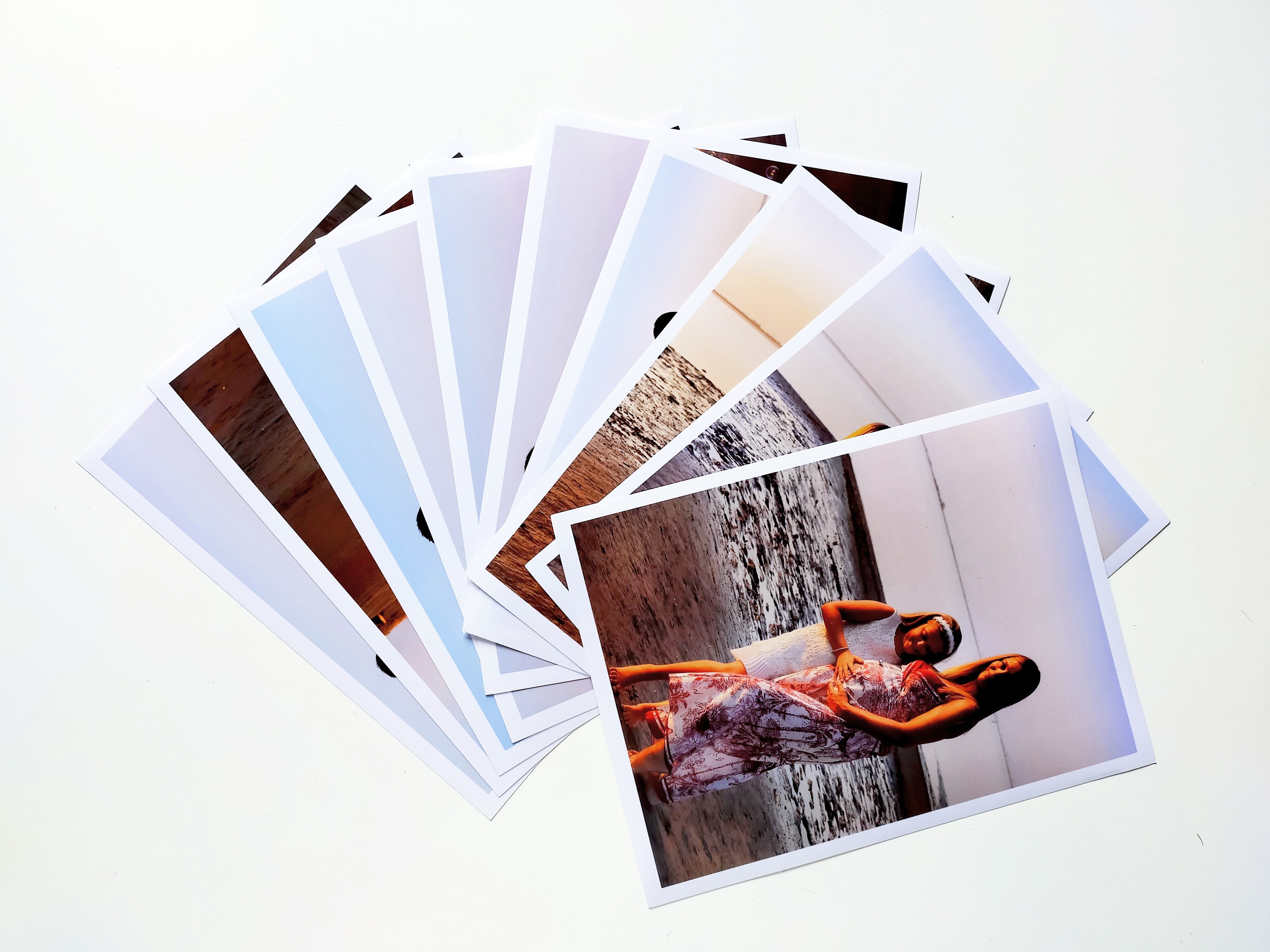 Ventaglio di stampe fotografiche su carta lucida, disposte a raggiera su sfondo bianco